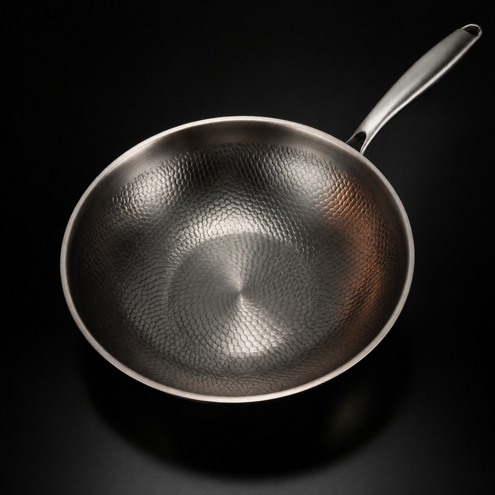 Draufsicht in die leere Pfanne, die das gleichmäßige Hammerschlagmuster der Innenfläche und den langen Metallgriff zeigt. 2