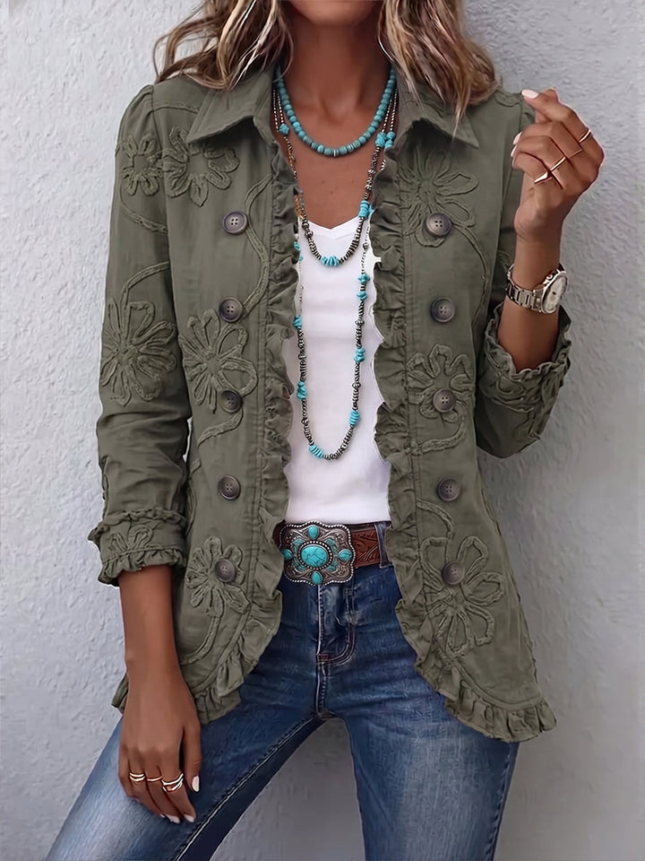 Frontansicht der olivgrünen Jacke mit Rüschenkante und Blumenstickerei, getragen über weißem Shirt und Jeans 1