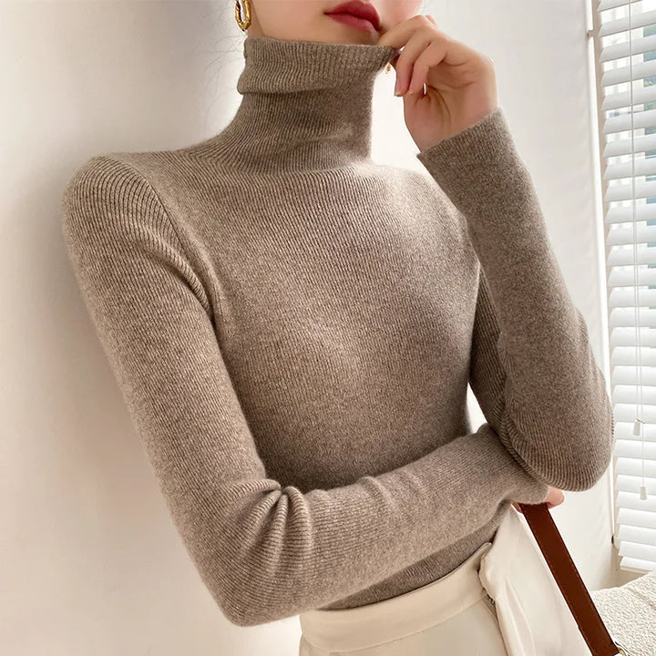 Graubrauner Rollkragenpullover am Model, das den Kragen berührt, kombiniert mit heller Hose 6