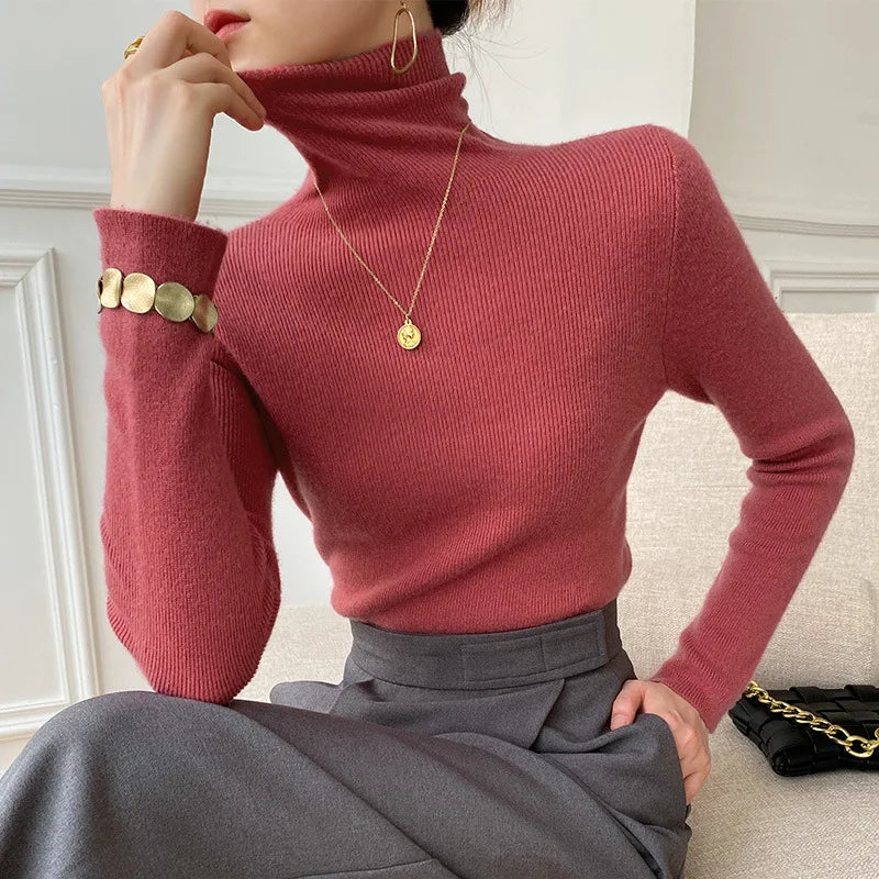 Roter bis beerenfarbener Rollkragenpullover am Model, kombiniert mit grauem Rock und goldenem Armschmuck 2
