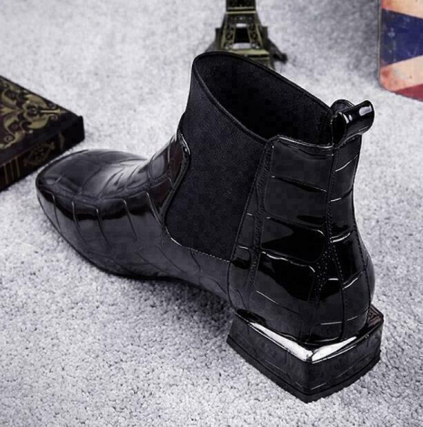 Schräge Rückansicht des Stiefels mit Blick auf Fersenpartie, Zuglasche und den kantigen Blockabsatz mit glänzendem Metalleffekt. 3