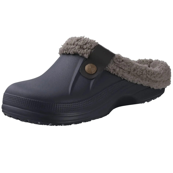 Dunkelblau-grauer Clog mit grauem Fellfutter und braunem Riemen mit Knopf, schräg von vorne freigestellt auf weißem Hintergrund. 3